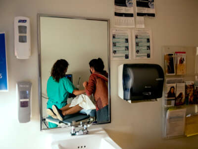 A patient recieves care from two medical professionals, as seen through a mirror reflecting them from behind