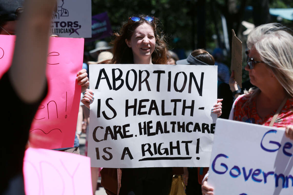 A protester holds a sign reading "ABORTION IS HEALTHCARE. HEALTHCARE IS A RIGHT" during ano outdoor protest