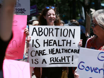A protester holds a sign reading "ABORTION IS HEALTHCARE. HEALTHCARE IS A RIGHT" during ano outdoor protest