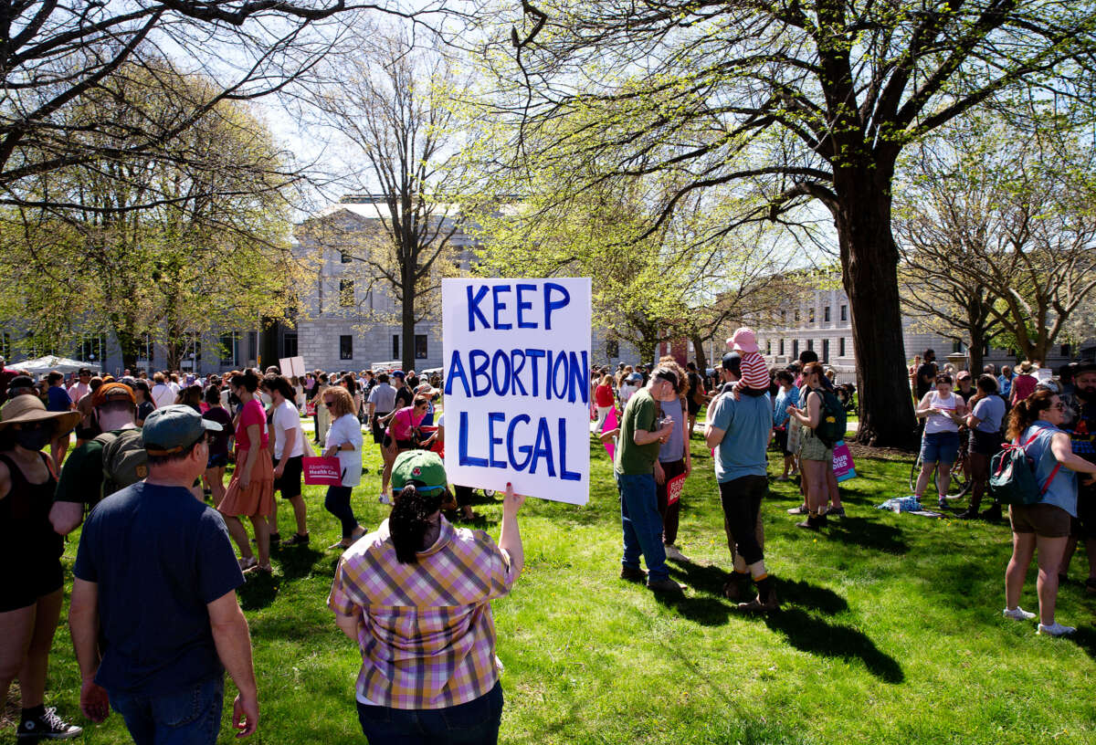 A protester holds a sign reading "KEEP ABORTION LEGAL" during an outdoor protest