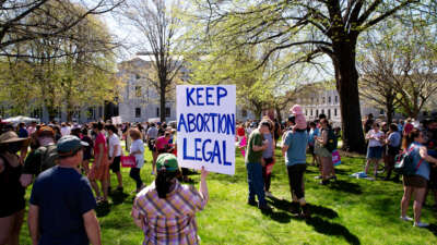A protester holds a sign reading "KEEP ABORTION LEGAL" during an outdoor protest