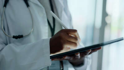 Close on a doctor's hands as they write on a tablet