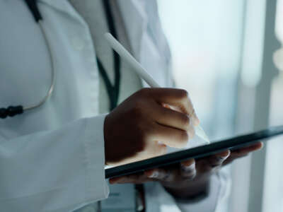 Close on a doctor's hands as they write on a tablet