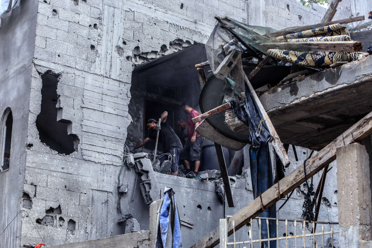 People shovel gravel while inside of a partially destroyed building