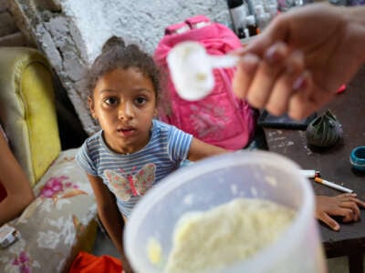 A 4-year-old child looks at the powdered milk her mother receives through Cuba's rationing system
