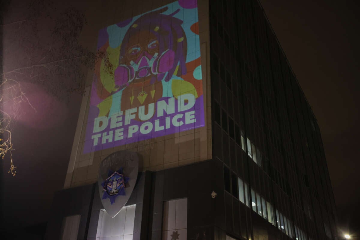 A protester projects ''Defund The Police'' on the wall of the Oakland Police Department as people gather at the Frank H. Ogawa Plaza following the police-perpetrated killing of Tyre Nichols by Memphis police, in Oakland, California, on January 29, 2023.