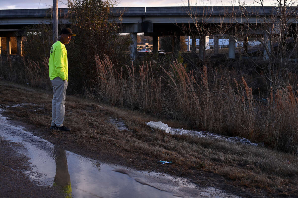 A contractor working for the City of Jackson watches as water from a damaged water main break runs along McLaurin Road on December 29, 2022, in Jackson, Mississippi.