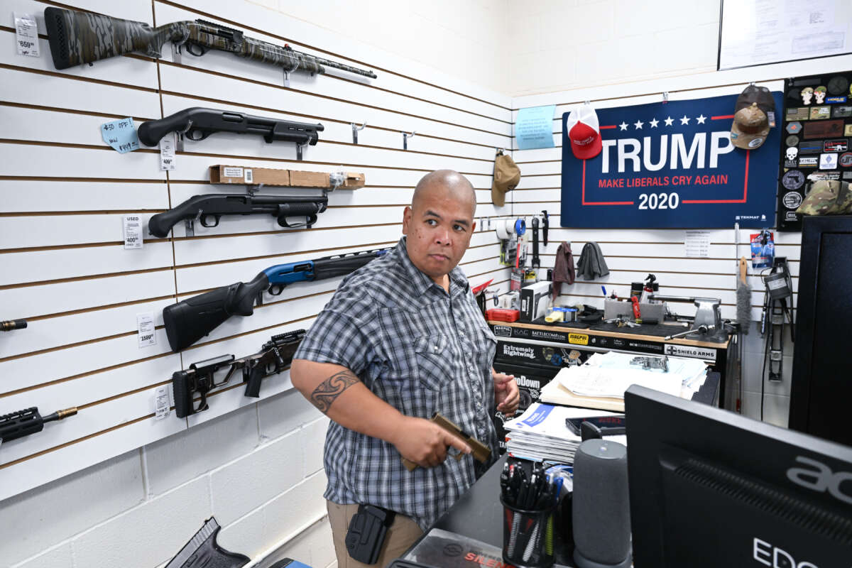 Tunis Lopez, owner of EDC TX gun store, puts on his firearm as the first customer of the day arrives on August 2, 2023, in New Braunfels, Texas.