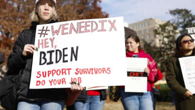 Activists hold up signs calling on U.S. President Joe Biden to finalize a new Title IX rule as they listen during a rally at Lafayette Park near the White House on December 5, 2023, in Washington, D.C.
