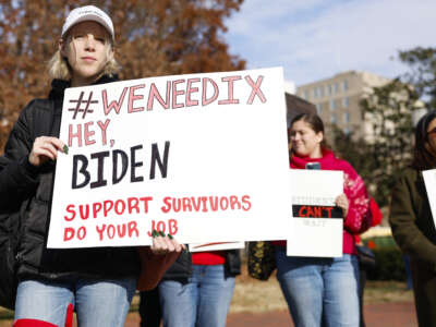 Activists hold up signs calling on U.S. President Joe Biden to finalize a new Title IX rule as they listen during a rally at Lafayette Park near the White House on December 5, 2023, in Washington, D.C.