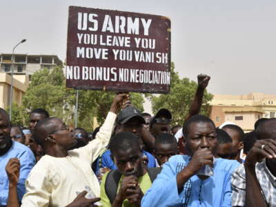 Protesters react as a man holds up a sign demanding that soldiers from the United States Army leave Niger without negotiation during a demonstration in Niamey, Niger, on April 13, 2024.