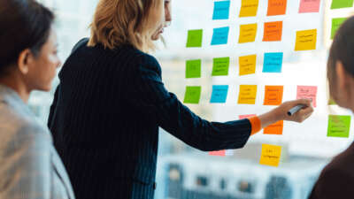 People conduct business meeting with sticky notes on glass wall
