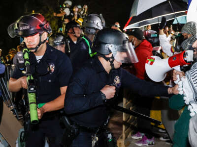 Police react while pro-Palestinian students stand their ground after police breached their encampment at the campus of the University of California, Los Angeles (UCLA) in Los Angeles, California, early on May 2, 2024.