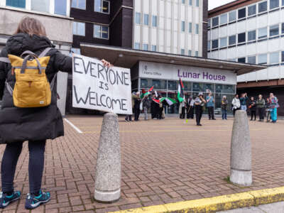 A protester holds a sign reading "EVERYONE IS WELCOME" at an outdoor protest