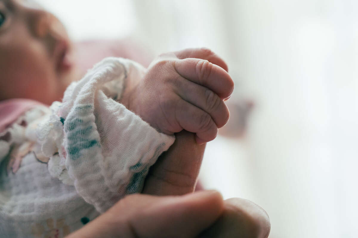 Baby holds parents finger in close-up