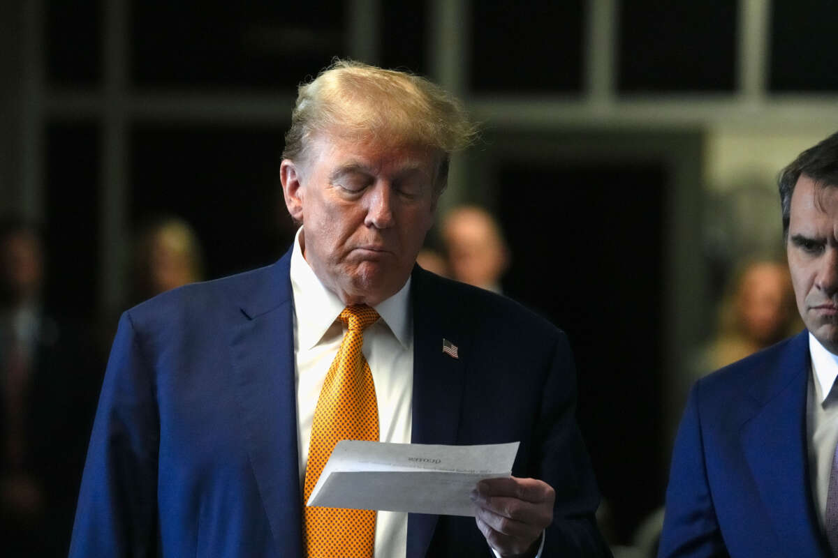Former President Donald Trump looks at a piece of paper as he speaks to the media at his trial for allegedly covering up hush money payments at Manhattan Criminal Court on May 7, 2024, in New York City.