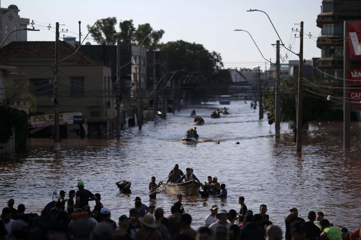Volunteers form a human corridor to receive boats with people rescued from flooded areas at the Sao Joao neighborhood in Porto Alegre, Rio Grande do Sul state, Brazil, on May 7, 2024.