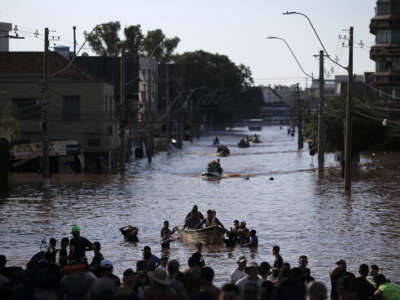 Volunteers form a human corridor to receive boats with people rescued from flooded areas at the Sao Joao neighborhood in Porto Alegre, Rio Grande do Sul state, Brazil, on May 7, 2024.