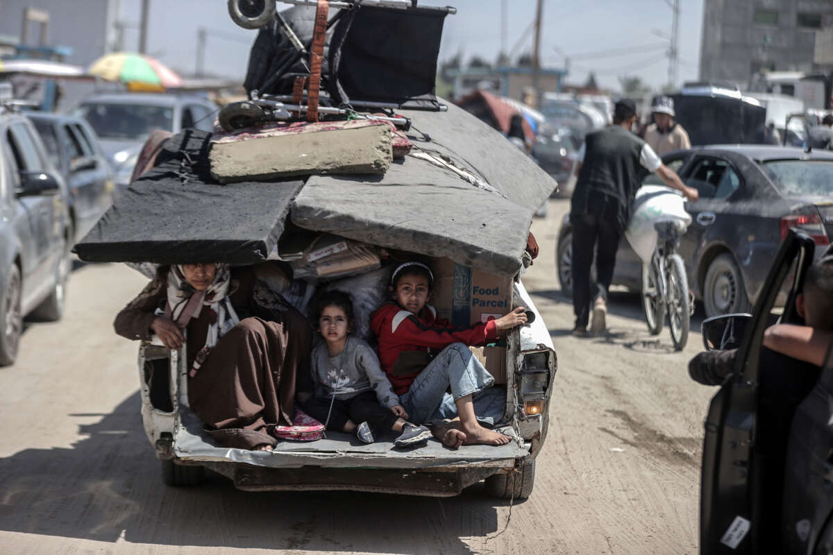 Palestinians sit in the back of a truck with their packed belongings as they depart from the eastern neighborhoods of the city due to ongoing Israeli attacks in Rafah, Gaza, on May 8, 2024.