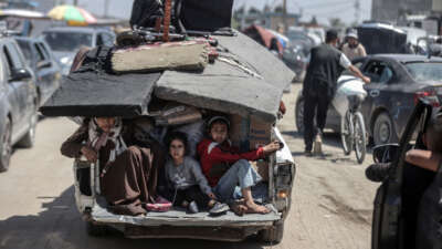 Palestinians sit in the back of a truck with their packed belongings as they depart from the eastern neighborhoods of the city due to ongoing Israeli attacks in Rafah, Gaza, on May 8, 2024.