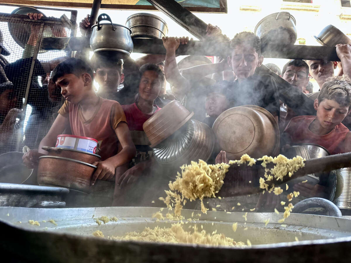 Children line up to receive a bowl of food for their families from charity organizations, in Rafah, Gaza, on May 3, 2024.