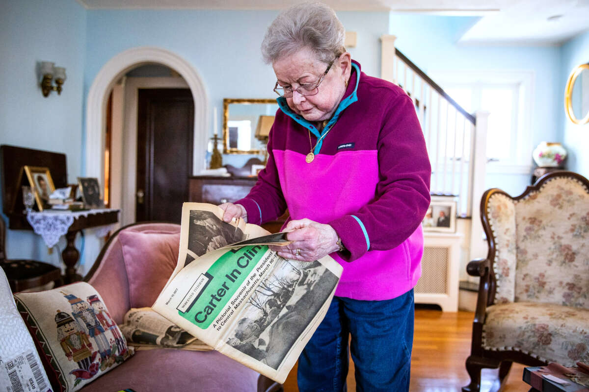 An elderly woman opens up a vintage newspaper