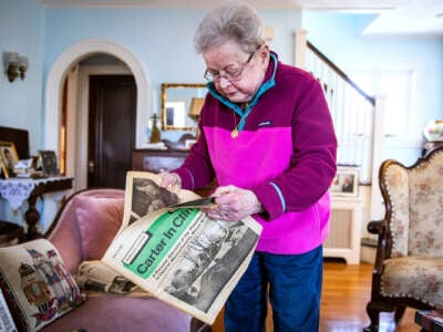 An elderly woman opens up a vintage newspaper