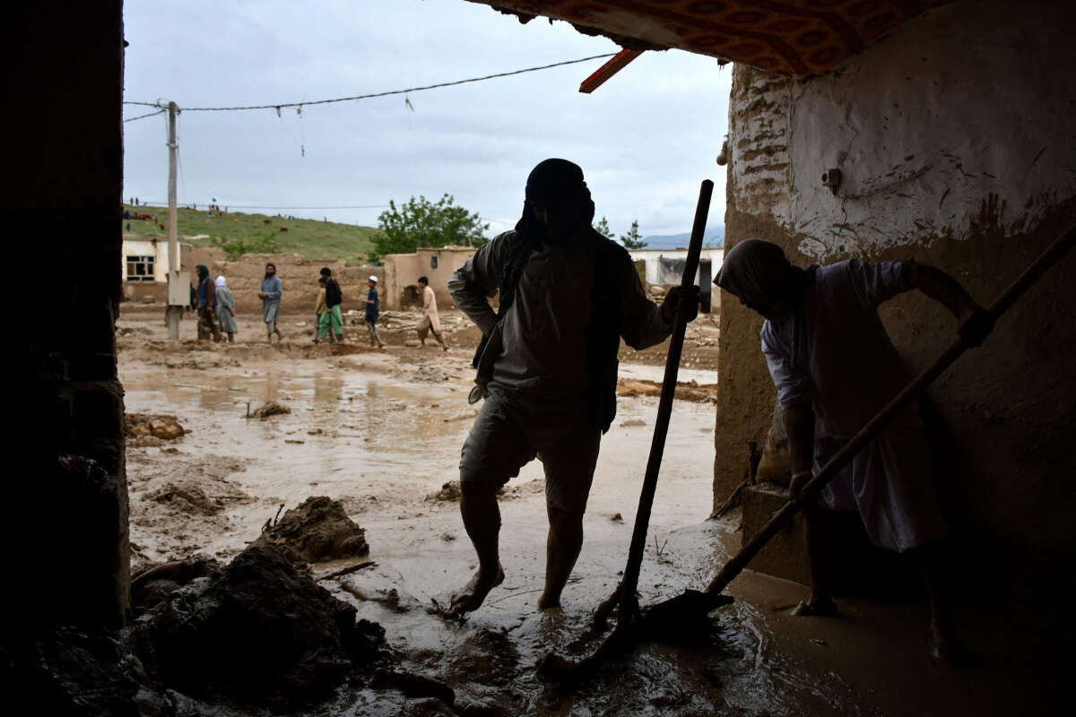 Afghan men shovel mud from a house following flash floods after heavy rainfall at a village in Baghlan-e-Markazi district of Baghlan province on May 11, 2024.