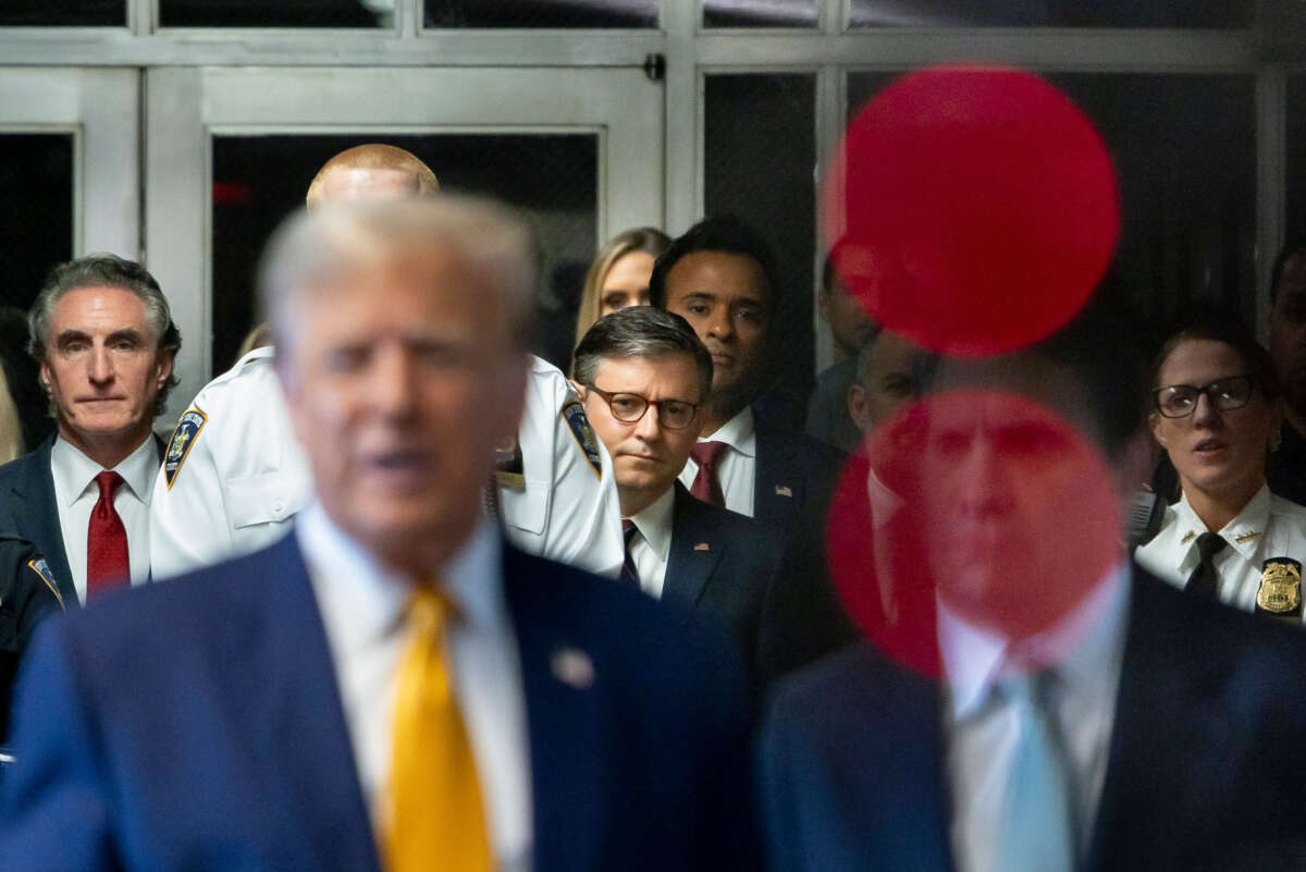 Speaker of the House Mike Johnson (center) listens as former President Donald Trump (foreground) talks with reporters as he arrives for his trial for allegedly covering up hush money payments linked to an extramarital affair with Stormy Daniels, at Manhattan Criminal Court on May 14, 2024, in New York City.