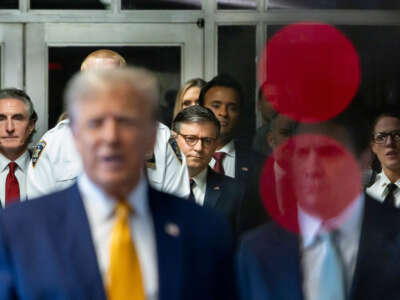 Speaker of the House Mike Johnson (center) listens as former President Donald Trump (foreground) talks with reporters as he arrives for his trial for allegedly covering up hush money payments linked to an extramarital affair with Stormy Daniels, at Manhattan Criminal Court on May 14, 2024, in New York City.
