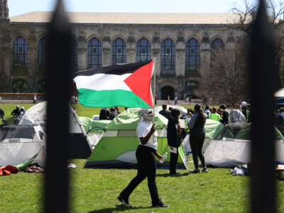 A student waving a Palestinian flag walks among the tents in an encampment at Northwestern University on April 25, 2024, in Evanston, Illinois.