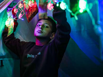 A boy strings up lights in his tent for Eid