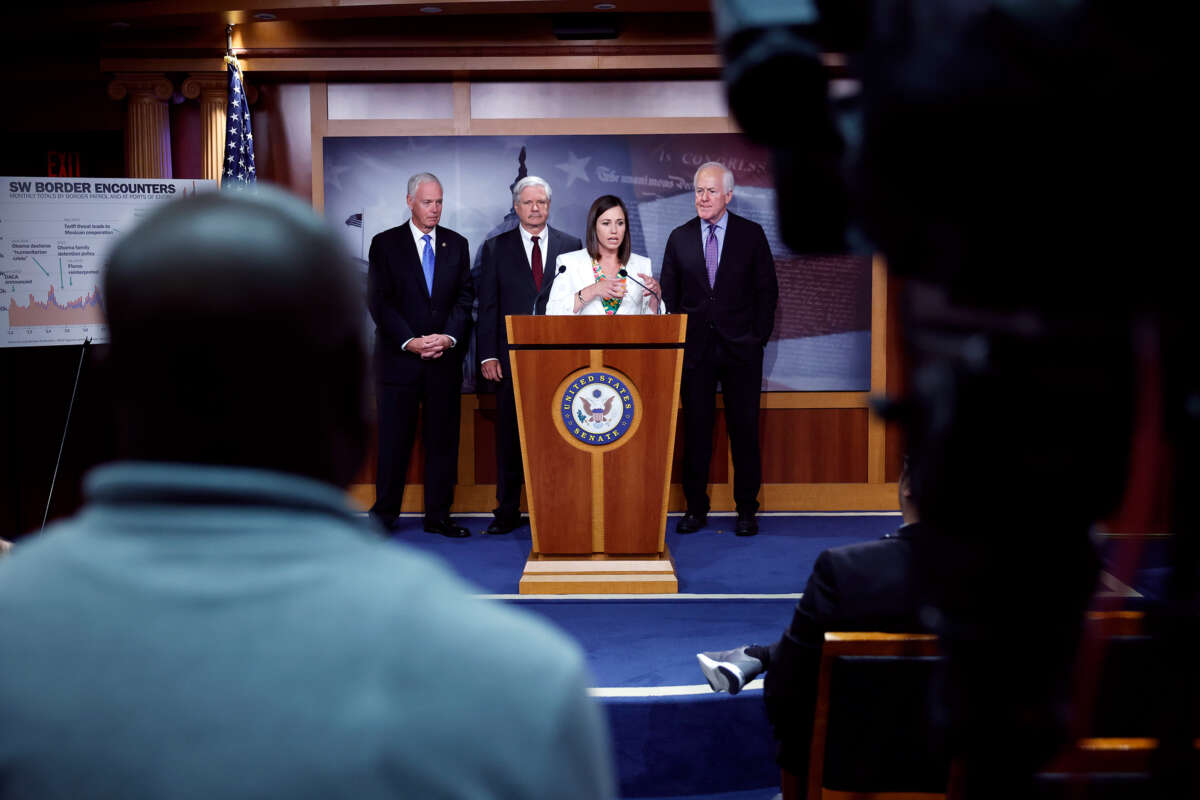 Katie Britt speaks at a podium as Mitch Mcconnell and two other republicans stand behind her