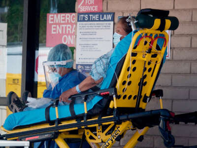 An elder is wheeled into a hospital in a gurney by medical professionals