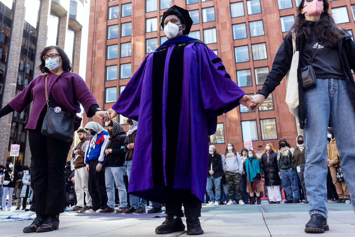 A faculty member of New York University holds hands with other protesters