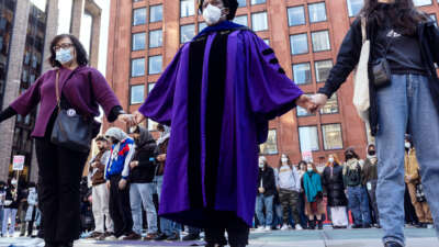 A faculty member of New York University holds hands with other protesters