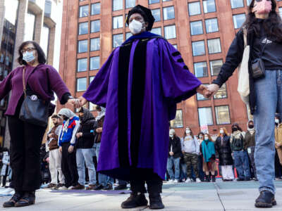 A faculty member of New York University holds hands with other protesters