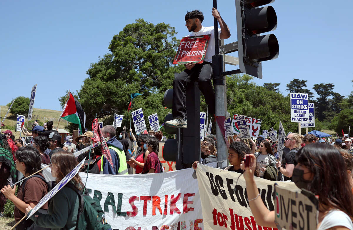 People displaying UAW signs and Palestinian flags rally during a demonstration