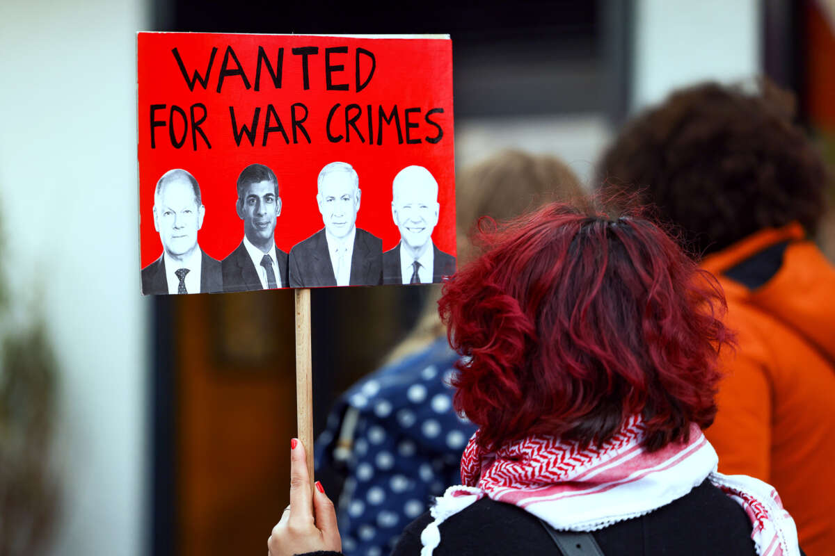 A protester holds a sign bearing the faces of German Chancellor Olaf Scholz, British Prime Minister Rishi Sunak, Israeli Prime Minister Benjamin Netanyahu and US President Joe Biden, beneath the words "WANTED FOR WAR CRIMES"