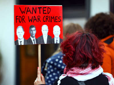 A protester holds a sign bearing the faces of German Chancellor Olaf Scholz, British Prime Minister Rishi Sunak, Israeli Prime Minister Benjamin Netanyahu and US President Joe Biden, beneath the words "WANTED FOR WAR CRIMES"