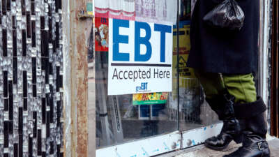 A person enters a store with a prominently displayed sign reading "EBT Accepted Here"