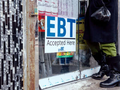 A person enters a store with a prominently displayed sign reading "EBT Accepted Here"