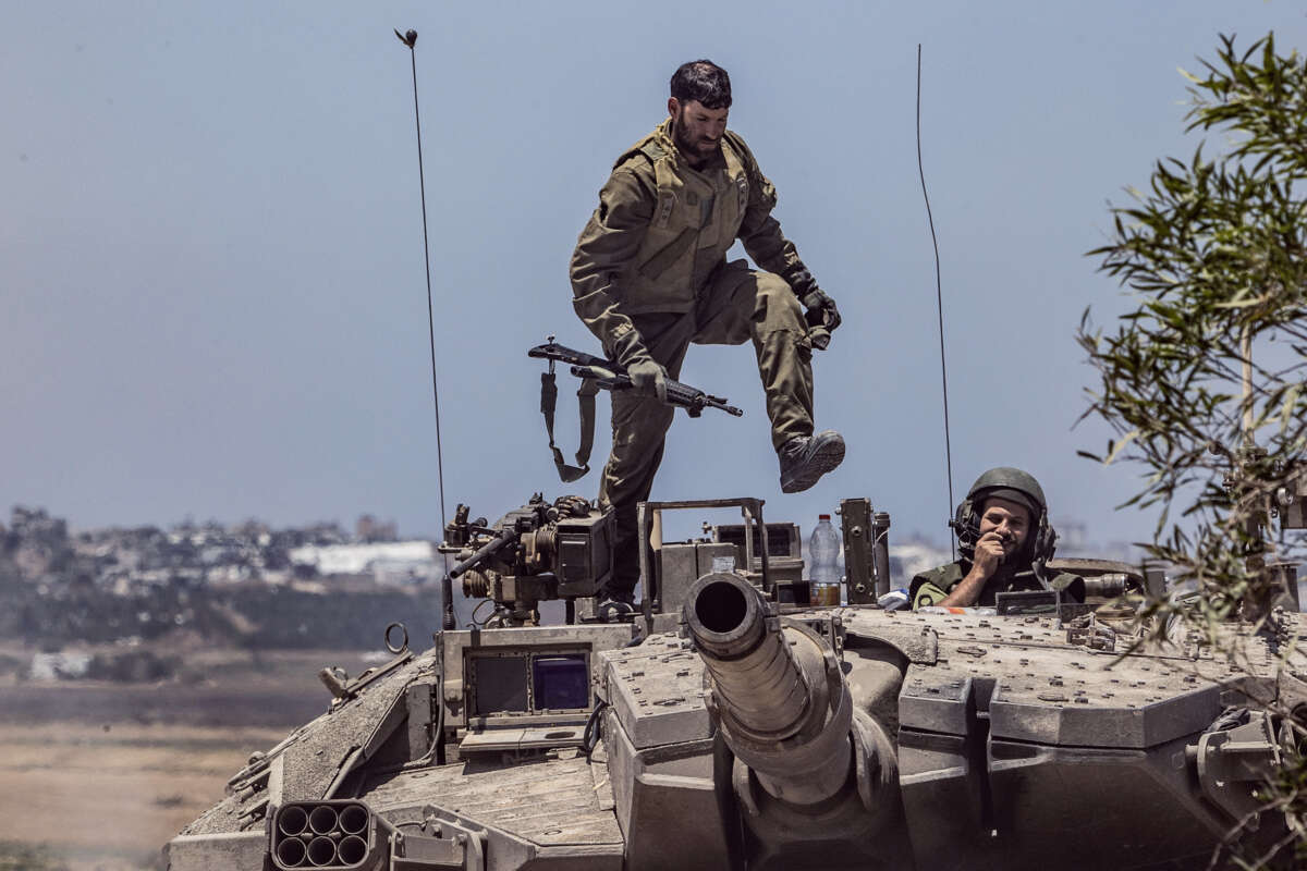 An idf soldier stomps on the roof of a tank