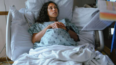 A pregnant Hawaiian woman lies in a hospital bed and speaks with her doctor while in labor.