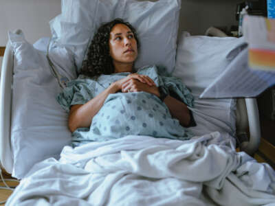 A pregnant Hawaiian woman lies in a hospital bed and speaks with her doctor while in labor.