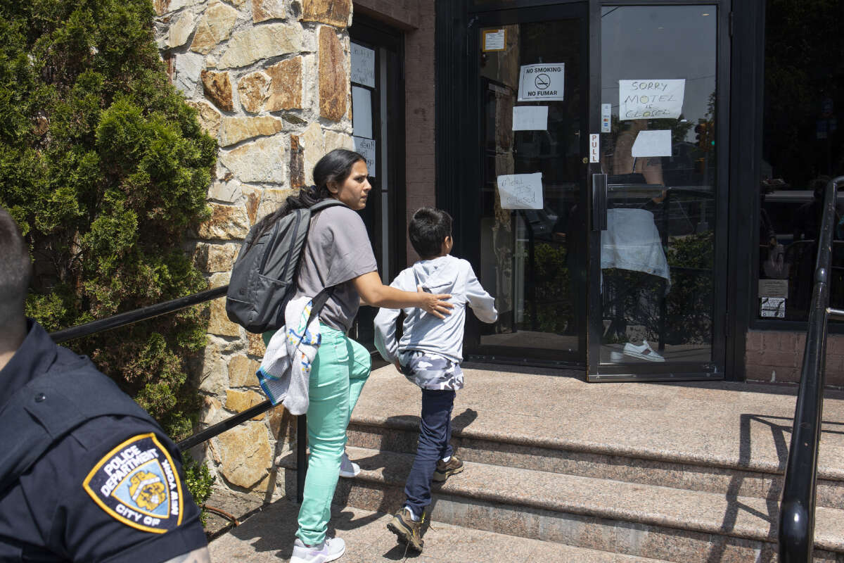 A migrant mother rushes her family past a small group of right-wing demonstrators trying to shut down a motel that is housing migrant immigrants, on May 30, 2023, in Queens, New York.