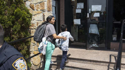 A migrant mother rushes her family past a small group of right-wing demonstrators trying to shut down a motel that is housing migrant immigrants, on May 30, 2023, in Queens, New York.
