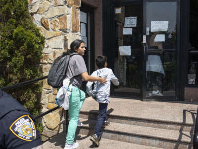 A migrant mother rushes her family past a small group of right-wing demonstrators trying to shut down a motel that is housing migrant immigrants, on May 30, 2023, in Queens, New York.