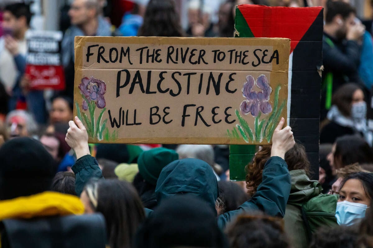 A pro-Palestinian activist holds up a sign reading 'From The River To The Sea Palestine Will Be Free' during a sit-down protest inside Charing Cross railway station to call for an immediate ceasefire in Gaza on November 4, 2023, in London, United Kingdom.