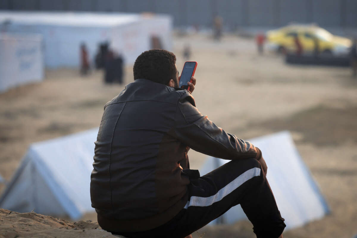 A displaced Palestinian man uses the phone in a refugee camp